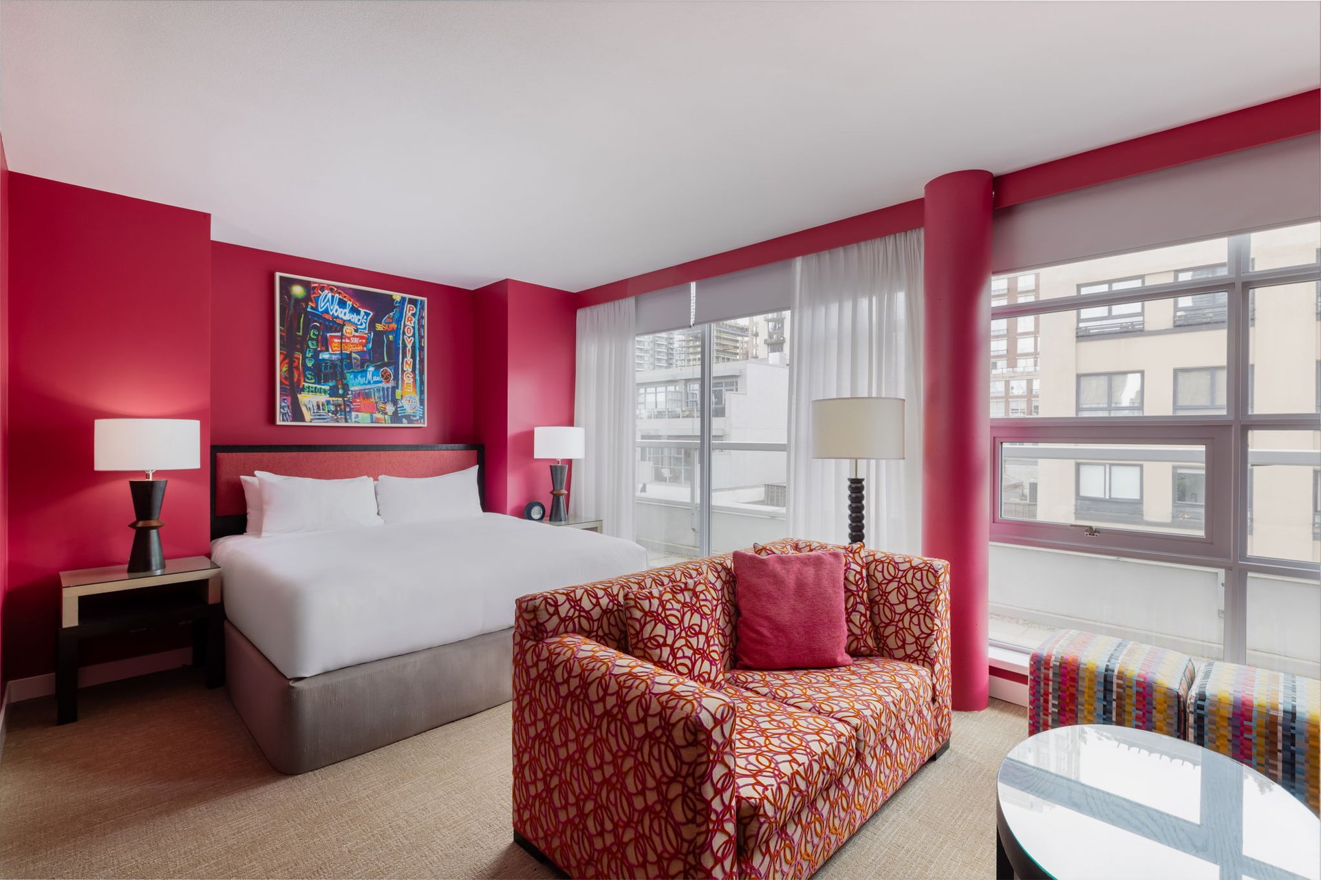 Opus Balcony Studio with red walls, a king bed, a patterned sofa, and city-view windows