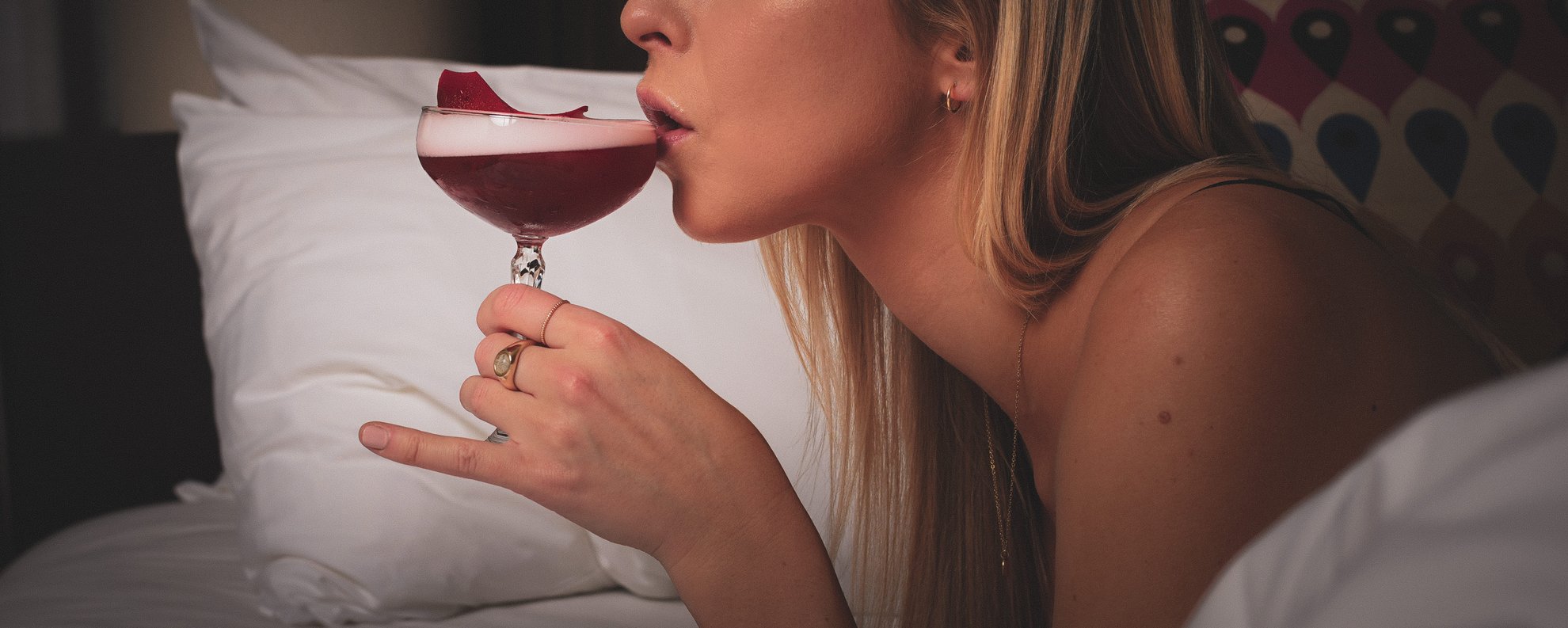 girl in bed sipping a cocktail
